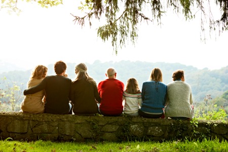 several generations sitting on stone wall facing away