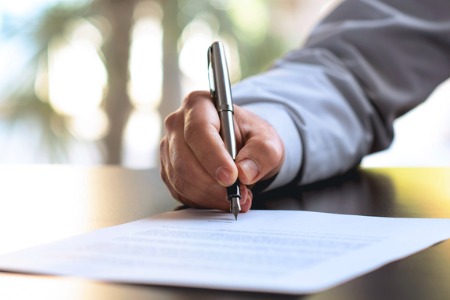 man's hand signing document